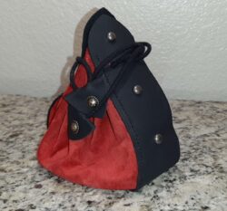 A Viking-inspired dice bag made from crimson chrome tan leather with black textured accents, finished with antique nickel studs and medallions.