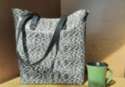 An everyday tote bag made from snake-pattern chrome tanned leather with black textured straps and hand stitching in white Ritza Tiger Thread.