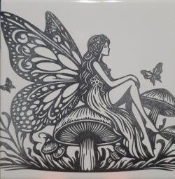 A laser-engraved ceramic tile featuring a detailed fairy-on-mushroom scene, engraved from licensed artwork.