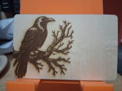 A laser-engraved birch wood business card featuring a detailed crow design — perfect for an assassin, a Poe fan, or anyone who prefers their branding a little darker.